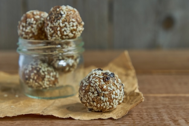 Trufas de proteína crua vegan saborosa ou bolas de energia com ameixas, sementes e nozes em uma jarra em madeira