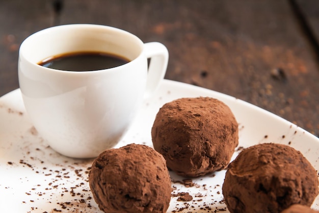 Foto trufas espolvoreadas con cacao en plato con taza de café