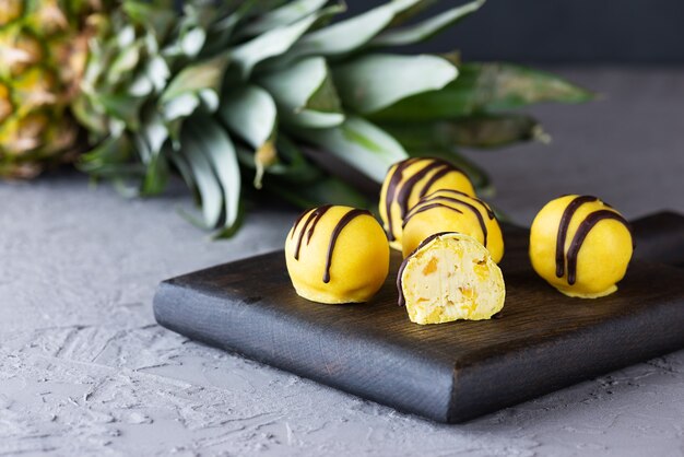 Trufas veganas em chocolate amarelo em uma placa de madeira. sem açúcar, lactose e sem glúten.