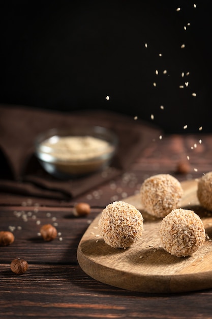 Trufas veganas orgánicas hechas de avellanas y dátiles con chispitas de sésamo servidas en mesa de madera