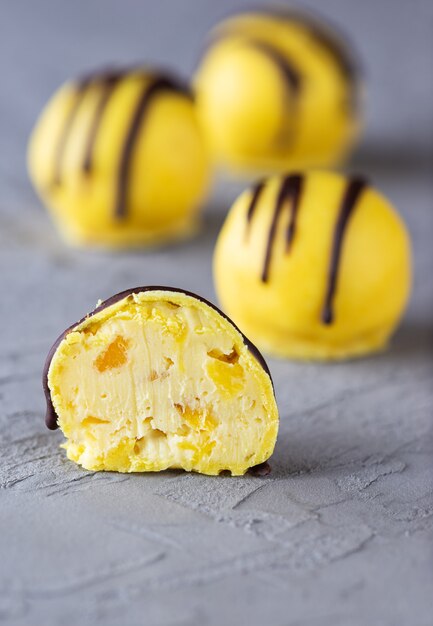 Trufas veganas con piña y mango sobre fondo gris azúcar sin gluten y sin lactosa