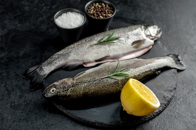 truta de peixe cru com especiarias prontas para cozinhar em um fundo de pedra