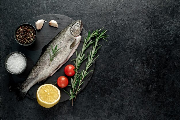 truta de peixe cru com especiarias prontas para cozinhar em um fundo de pedra