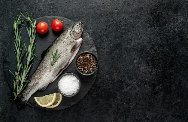 truta de peixe cru com especiarias prontas para cozinhar em um fundo de pedra