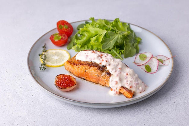 Truta salmão com molho cremoso de champanhe com caviar vermelho rúcula tomate cereja rabanete e limão prato tradicional francês foco seletivo closeup