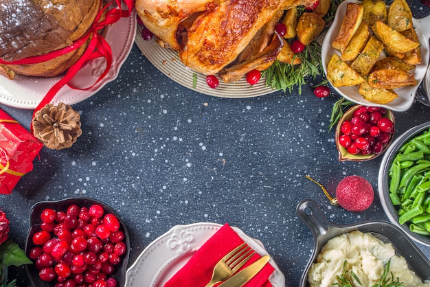 Truthahnessen zu Weihnachten oder Silvester. Gebackener Truthahn mit Kartoffeln, roten Beeren und Salbeiblättern, auf dem Weihnachtstisch mit Weihnachtsbaum, Geschenk und Kerzenhintergrund