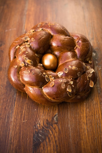 Tsoureki tradicional pão doce de Páscoa grego, guarnecido com amêndoas lascadas e decorado com um ovo tingido de vermelho cozido no meio