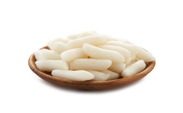 Tteok ou bolos de arroz coreano em placa de madeira isolada no fundo branco.