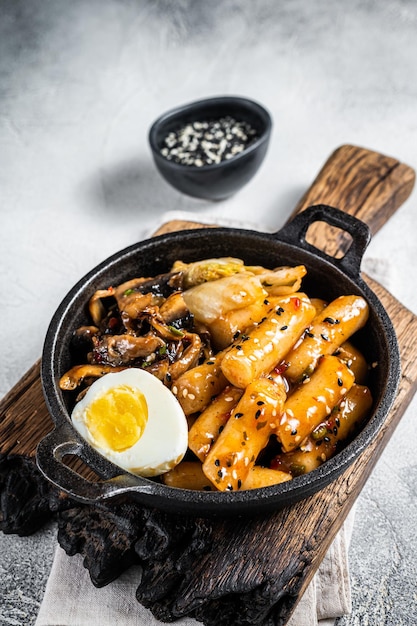 Tteokbokki Topokki-Stick-Reiskuchen in würziger Sauce mit Ei und Pilzen Weißer Hintergrund Ansicht von oben