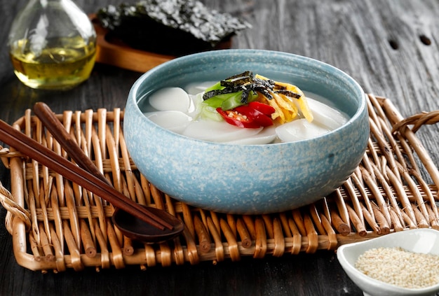 Tteokguk ou sopa de bolo de arroz fatiado, prato tradicional coreano comido durante a celebração do ano novo coreano seollal, closeup na tigela na mesa de madeira, horizontal