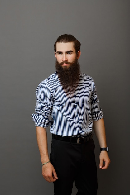 Tu hombre con barba fotografiado en una pared gris