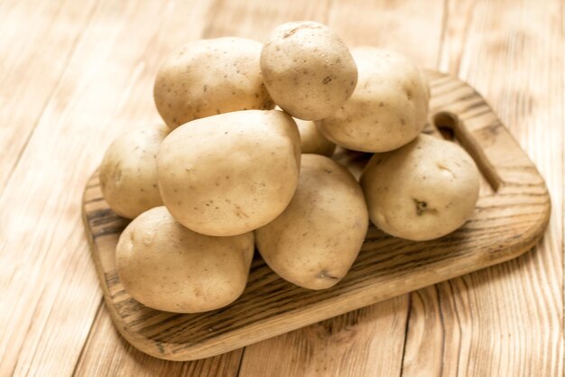 Tubérculos de batata crua em um fundo de madeira