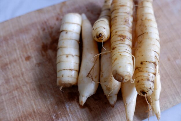 Foto los tubérculos limpiados de irut maranta arundinacea en una tabla de corte de madera foto de stock de alimentos saludables