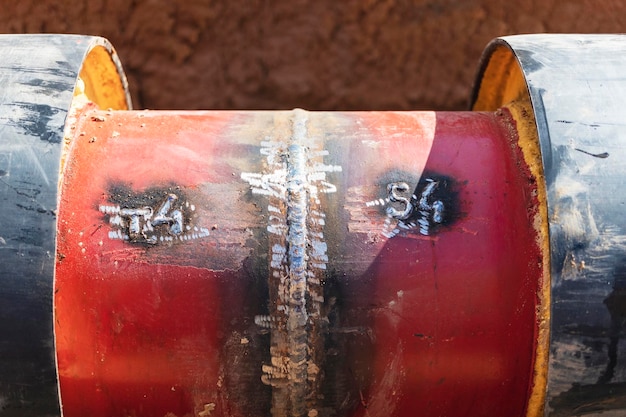 Tubería aislada Grandes tuberías de metal con una funda de plástico colocadas en una zanja Soldadura de tuberías en un pozo en un sitio de construcción