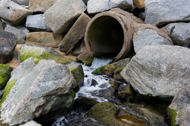 Una tubería está rodeada de rocas y el agua está rodeada de rocas.