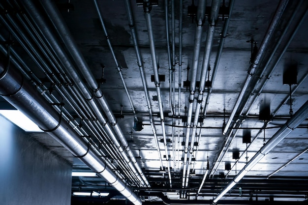 Tuberías de sistema sanitario y cables eléctricos instalados bajo estructura de losa plana de hormigón armado en edificio Tuberías de ventilación en Estacionamiento Subterráneo