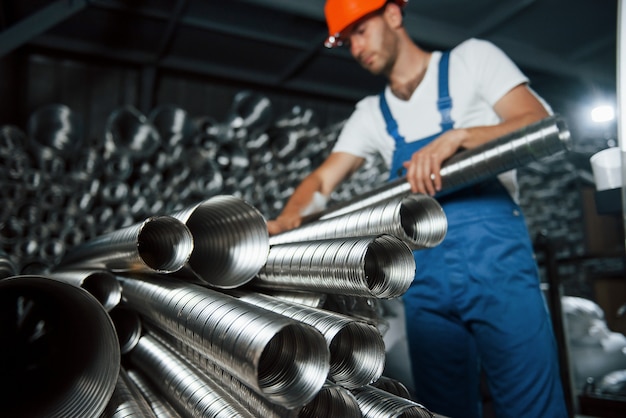 Tuberías de ventilación de color plateado. El hombre de uniforme trabaja en la producción. Tecnología industrial moderna.