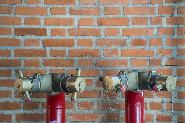 Tubo de agua de hidrante rojo contra la pared de ladrillos.