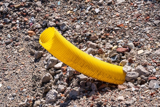 Tubo corrugado amarillo que sobresale del suelo cubierto de piedras