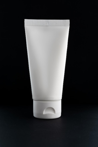 tubo cosmético blanco sobre fondo negro El concepto de una crema con ingredientes naturales y sin pruebas en animales