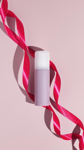 Tubo cosmético de plástico en blanco con cintas rosadas Maqueta de marca de productos de belleza cosméticos Espacio para copiar