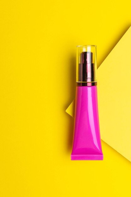 Tubo cosmético rosa brilhante em fundo amarelo Cuidados modernos da pele e beleza Imagem conceitual
