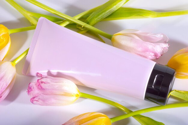 Tubo cosmético rosa e vista superior de tulipas