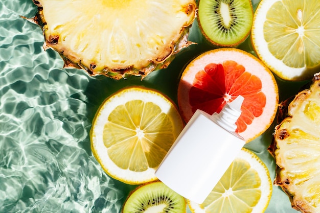 Tubo de creme de produtos de beleza com frutas cítricas limão kiwi laranja abacaxi toranja limão água superfície transparente