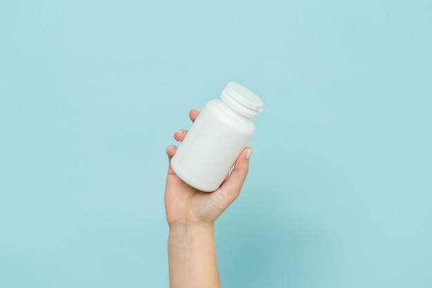 Tubo de plástico branco na mão feminina Garrafa para cápsula de pílula ou suplemento Maquete de marca de produto
