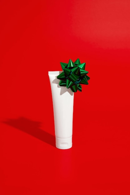 Tubo de plástico cosmético branco em branco sobre fundo vermelho com conceito de venda do dia dos namorados de Natal