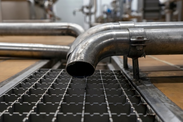 Tubo de drenaje y drenaje de agua del acero inoxidable utilizado en la industria alimentaria. Desagüe de piso en el primer plano de la instalación de fabricación.