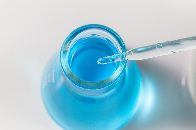 Tubo de ensayo de ciencia azul sobre fondo blancoPipette y platos de química aislado sobre fondo blanco.