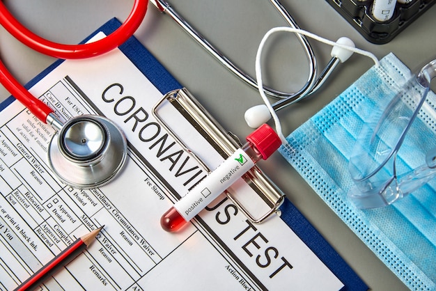 Un tubo de ensayo con una muestra de sangre negativa para la prueba COVID-19 en el formulario de prueba de coronavirus.