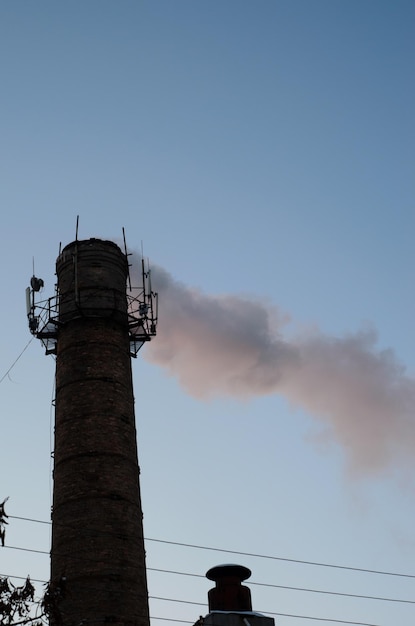 Tubo industrial y humo contra el cielo.