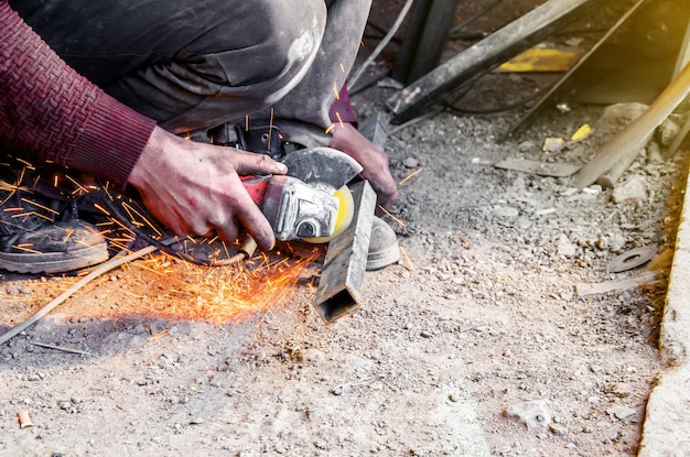 Tubo de metal de corte manual con una sierra circular Trabajador de manos saltando chispas