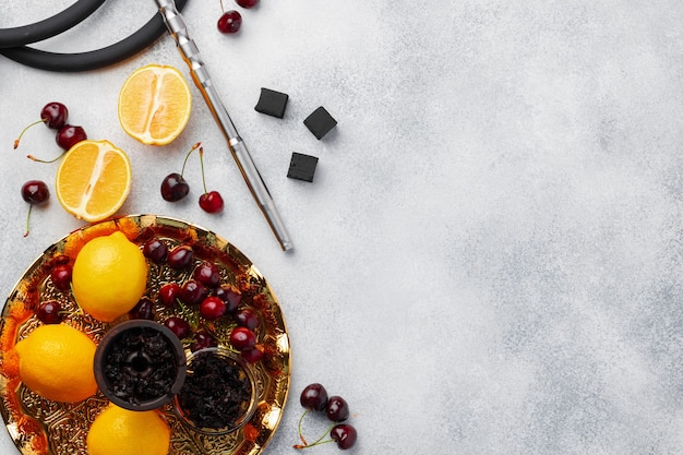 Tubo de narguile y eje con frutas en pared gris, cerrar