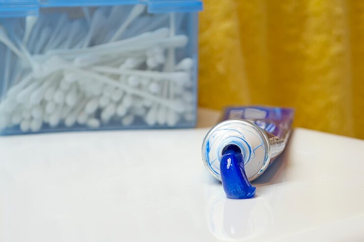 Foto tubo de pasta de dientes exprimido y caja de hisopos de algodón en un fregadero