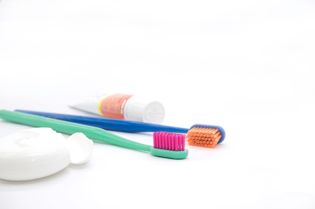 Tubo de pasta de dientes pack hilo dental cepillos de dientes de colores con cerdas brillantes sobre un backgrou blanco