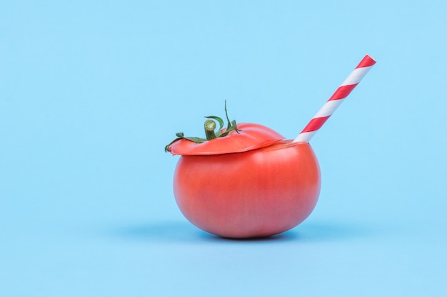 Un tubo rojo insertado en un tomate con la parte superior cortada.