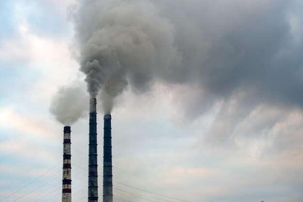 Tubos altos da usina de carvão com fumaça preta subindo para a atmosfera poluente.