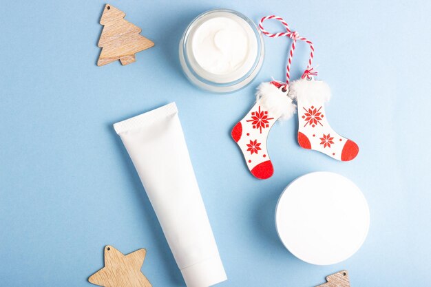 Tubos brancos com cosméticos em um fundo azul com decorações de natal produtos de cuidados com a pele de inverno banner de natal com espaço de cópia para texto