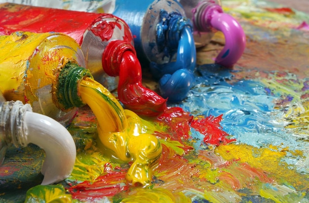 tubos com pintura a óleo de arte em uma paleta de pinturas de arte coloridas close-up