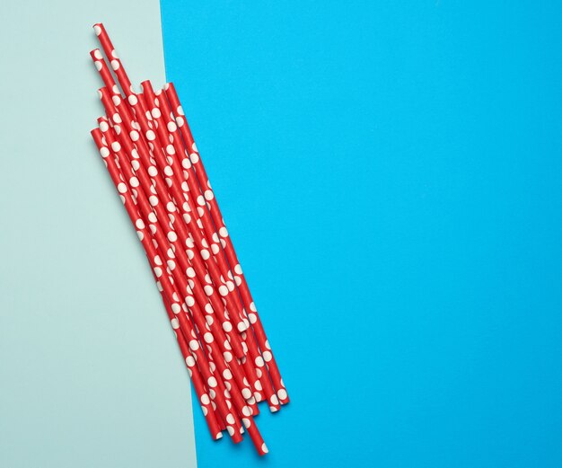 Tubos de coquetel de papel vermelho em um fundo azul, rejeição de plástico, desperdício zero, vista superior