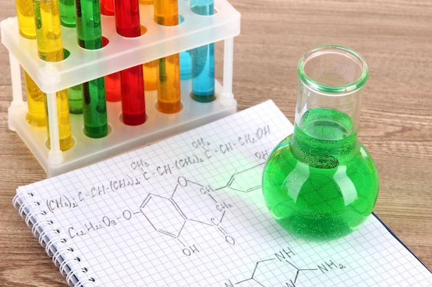 Tubos de ensaio com líquidos coloridos e fórmulas na mesa