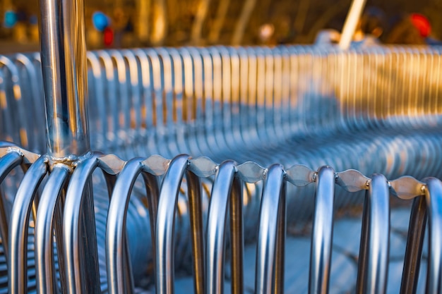 Tubos de metal de banco de rua de close-up dispostos paralelos uns aos outros em uma estrutura de rua. Conceito de materiais resistentes às intempéries e design industrial moderno. Espaço de publicidade