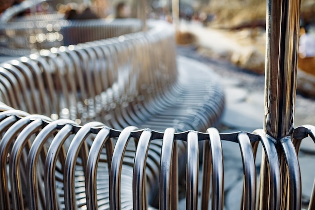 Tubos de metal de banco de rua de close-up dispostos paralelos uns aos outros em uma estrutura de rua. Conceito de materiais resistentes às intempéries e design industrial moderno. Espaço de publicidade