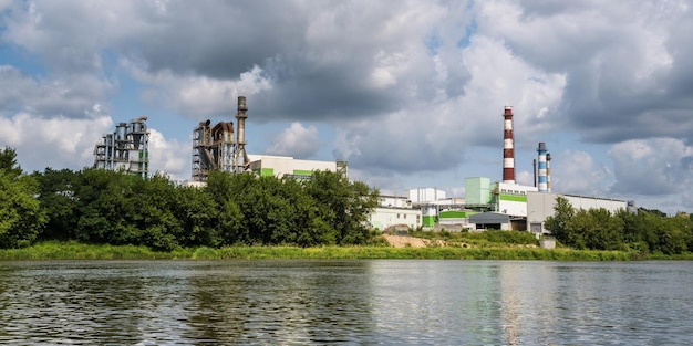 Tubos de serraria de fábrica de marcenaria perto do rio Conceito de poluição do ar Paisagem industrial poluição ambiental resíduos de usina termelétrica