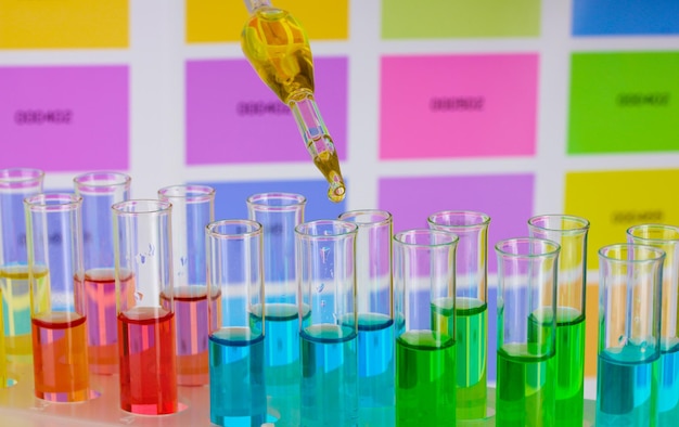 Tubos de ensayo con líquido de color y pipeta sobre fondo de muestras de color