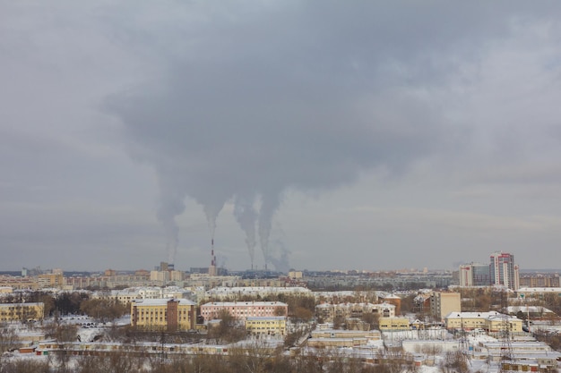 Tubos de humo en el horizonte - Paisaje industrial en la ciudad de nieve de invierno, gran angular