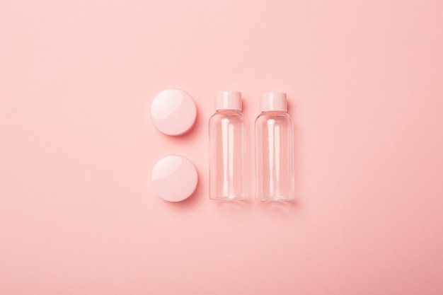 Tubos vacíos para cosméticos sobre una superficie rosa pastel